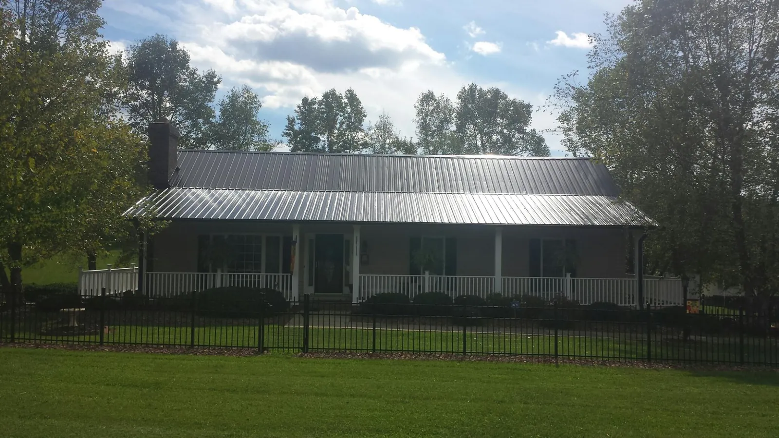 Gray metal roof on a brick ranch with a full width front porch — Gutter Guard Installation work by our crew in Medford